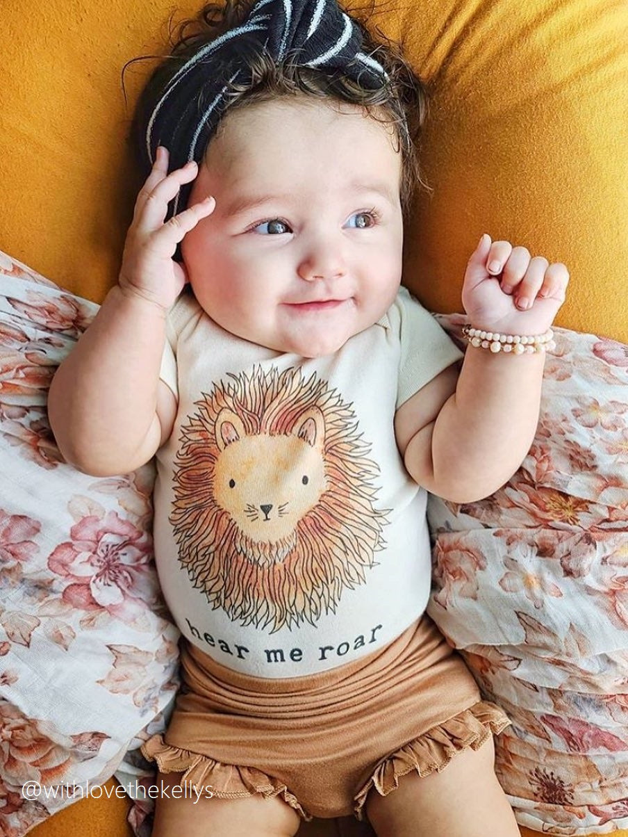 baby wearing mini + meep bear bodysuit with hear me roar lion print